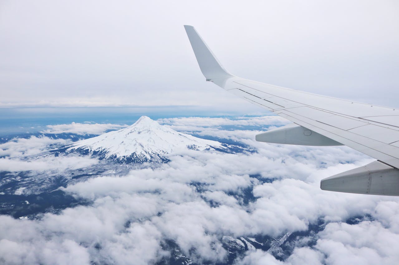 Services-03 Mountain peak and airplane wing seen from above the clouds, showcasing a beautiful aerial view.