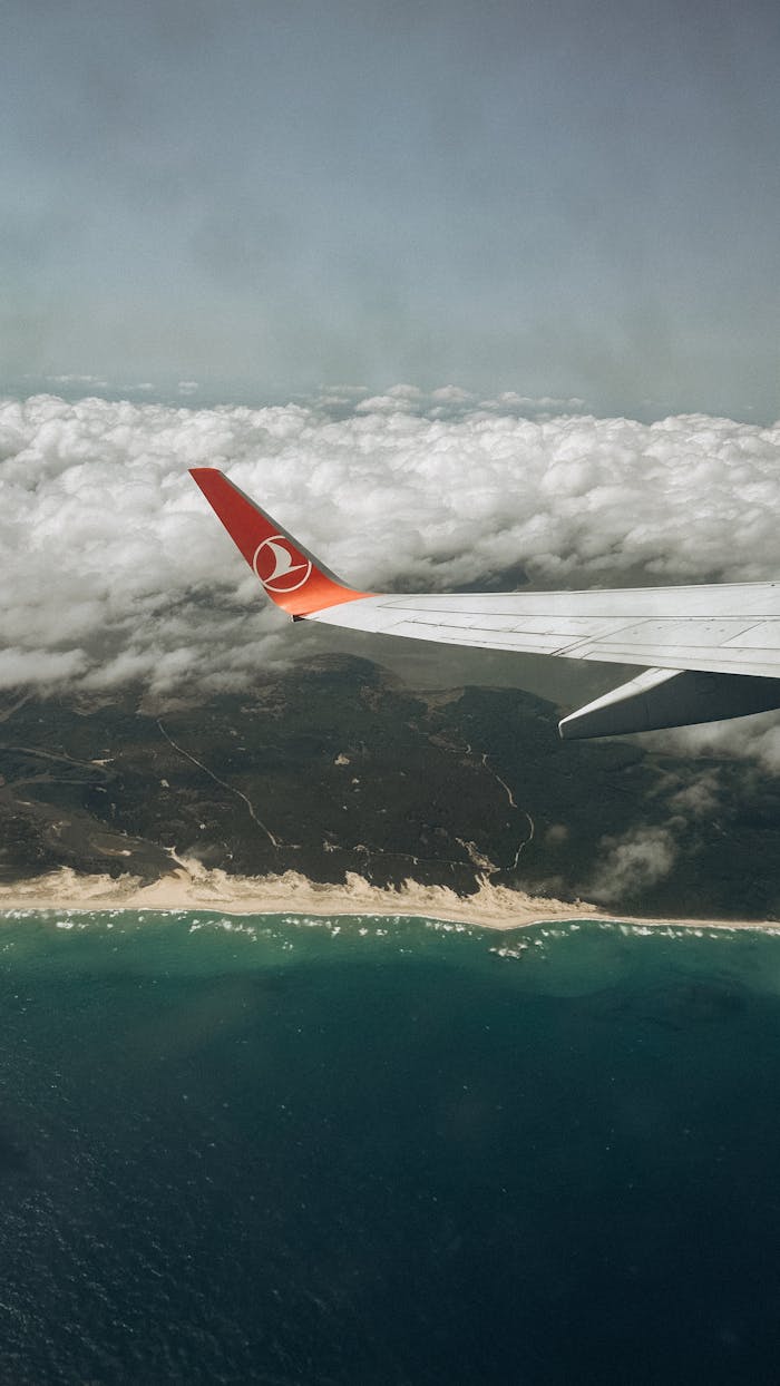 why-choose-us Aerial view from an airplane wing over a beautiful coastal landscape and ocean.